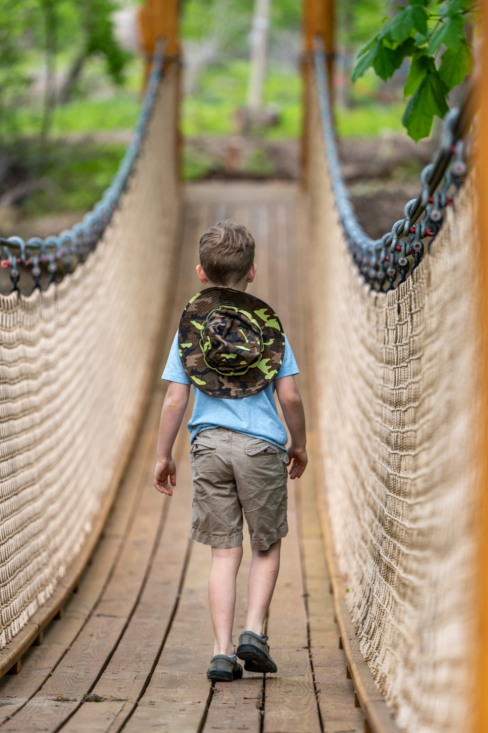 Boy crossing suspension bridge to Treehouse Village at Iowa Arboretum and Gardens